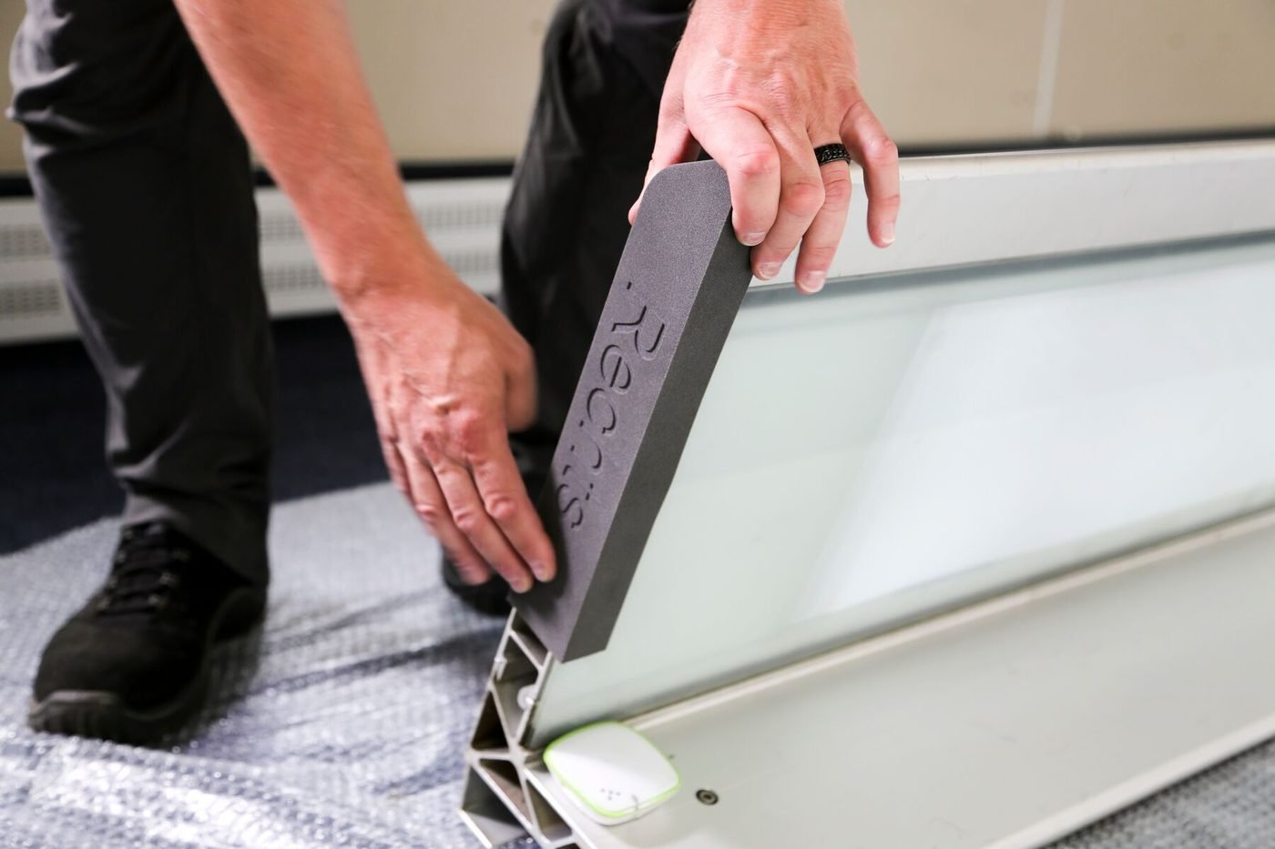 A technician fitting a long printed bracket to a vehicle panel
