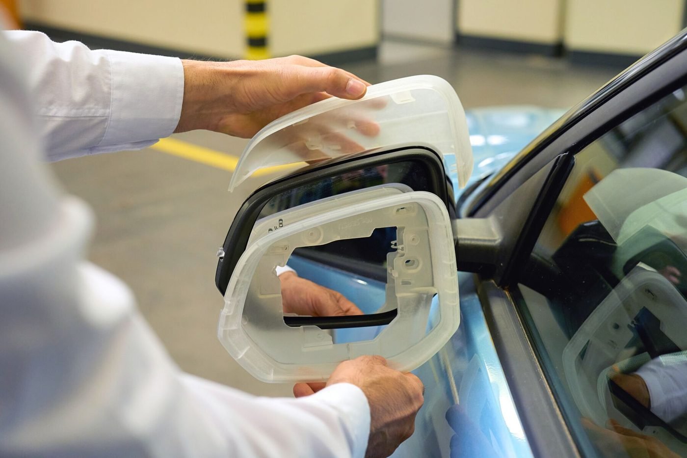 A clear printed prototype bracket being test fitted against a vehicle window frame